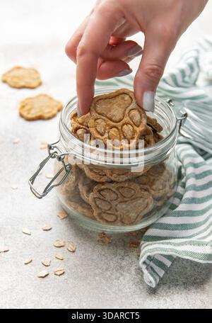 Frau Hand nimmt ein Pfotenmuster Haustier Leckerli aus einem Glas Stockfoto