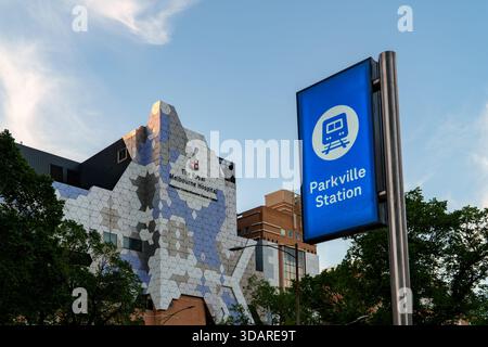 Melbourne, VIC, Australien. Dezember 2025. - Ein markantes blaues Schild für die Parkville Station steht vor dem einzigartigen Royal Melbourne Hospital Stockfoto