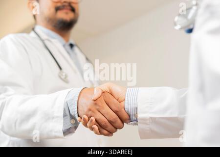 Nahaufnahme des Handschlags zwischen den beiden Sanitätern. Abgeschnittene Aufnahme einer Gruppe von Ärzten, die sich die Hände schütteln, bei der Besprechung im Krankenhaus vorstellt. Selektiver Fokus Stockfoto