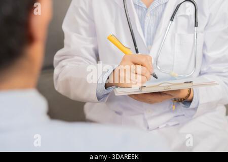 Abgeschnittene Aufnahme einer Ärztin in der Arztpraxis im Krankenhaus, mit Untersuchungsergebnissen auf Clipborad und Beratung mit Mann Patient Stockfoto