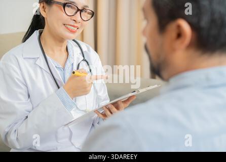 Medizin, Gesundheitswesen und Menschenkonzept. Glückliche Ärztin mit Klemmbrett, die mit reifem Mann Patient im Krankenhaus spricht Stockfoto