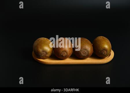 Lebendige Kiwi-Scheiben auf dunklem Hintergrund. Kontrastreiche, minimalistische Komposition mit Schwerpunkt auf frischem Obst, Vitaminen und gesunden Bio-Snacks. Stockfoto