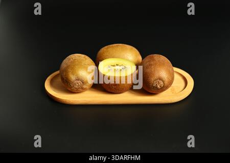 Lebendige Kiwi-Scheiben auf dunklem Hintergrund. Kontrastreiche, minimalistische Komposition mit Schwerpunkt auf frischem Obst, Vitaminen und gesunden Bio-Snacks. Stockfoto