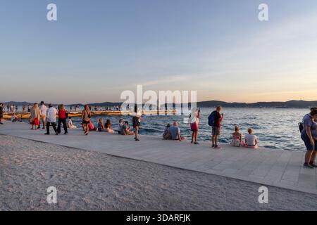 Zadar, Kroatien - 17. September 2025: Die Menschen versammelten sich am Ufer von Zadar und genossen die Adriaküste, während sie auf den stimmungsvollen, malerischen Sonnenuntergang über dem Meer warteten Stockfoto