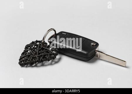 Autoschlüssel mit herzförmigem Schlüsselanhänger auf hellem Hintergrund Stockfoto