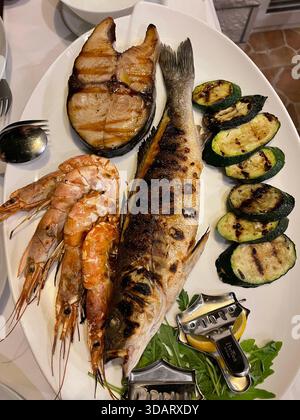 Lachssteak Medaillon und ganzer gegrillter Fisch serviert mit gegrillten Garnelen und gegrillten Auberginen und Zucchini. Draufsicht Stockfoto