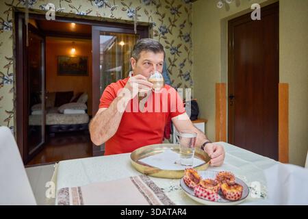 Morgens macht ein Mann mittleren Alters zu Hause Kaffee und serviert ihn. Stockfoto