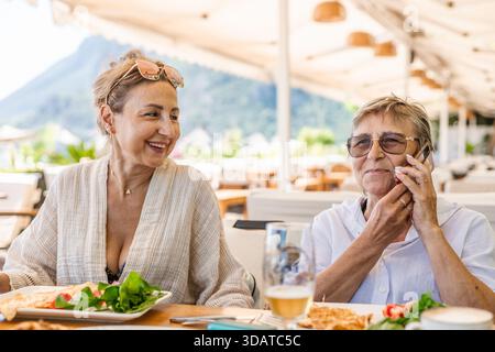Frau mittleren Alters mit Brille, die im türkischen Restaurant telefoniert Stockfoto