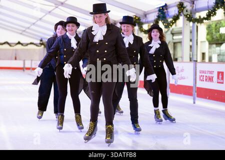 Anlässlich des World Ice Skating Day am 14. Dezember stellen Mitarbeiter der National Galleries of Scotland Schlittschuhlaufen eines der berühmtesten Gemälde aus Schottlands Sammlung nach, Sir Henry Raeburns Skating Minister. Zusammen mit Edinburghs Weihnachten gingen die Eislaufminister auf die Eislaufbahn in der George Street, um das Gemälde nachzuahmen. Das um 1795 gemalte Kunstwerk trägt den Namen Reverend Robert Walker Skating am Duddingston Loch, wurde aber liebevoll als Skating Minister bezeichnet. Bilddatum: Dienstag, 9. Dezember 2025. Stockfoto