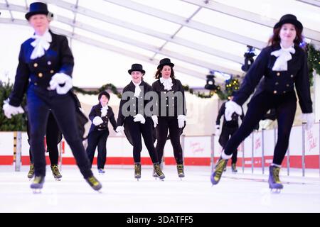 Anlässlich des World Ice Skating Day am 14. Dezember stellen Mitarbeiter der National Galleries of Scotland Schlittschuhlaufen eines der berühmtesten Gemälde aus Schottlands Sammlung nach, Sir Henry Raeburns Skating Minister. Zusammen mit Edinburghs Weihnachten gingen die Eislaufminister auf die Eislaufbahn in der George Street, um das Gemälde nachzuahmen. Das um 1795 gemalte Kunstwerk trägt den Namen Reverend Robert Walker Skating am Duddingston Loch, wurde aber liebevoll als Skating Minister bezeichnet. Bilddatum: Dienstag, 9. Dezember 2025. Stockfoto