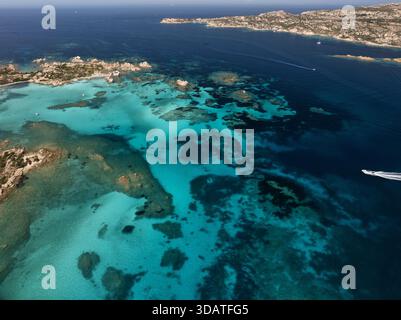 Aus der Vogelperspektive sehen Sie kristallklares türkisfarbenes Wasser mit felsigen Felsvorsprüngen und fernen Inseln unter dem hellen sonnigen Himmel, La Maddalena Archipel, Sardin Stockfoto