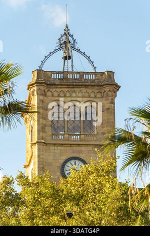 Blick auf einen alten Uhrenturm der Universität von barcelona, der hoch im grünen Laub steht, Barcelona, Katalonien, Spanien. Stockfoto