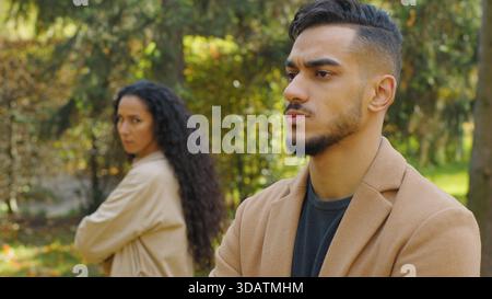 Frustrierter hispanischer Mann beleidigt wütend Trennung von verärgerter arabischer Frau Paarkonflikt im Herbst Park trauriger Freund Ehemann mit Freundin Stockfoto