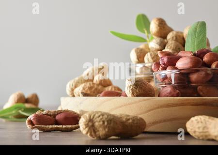 Geschälte und ungeschälte Erdnüsse in Glasschalen auf einem Holzteller auf der Küchenbank. Draufsicht. Stockfoto
