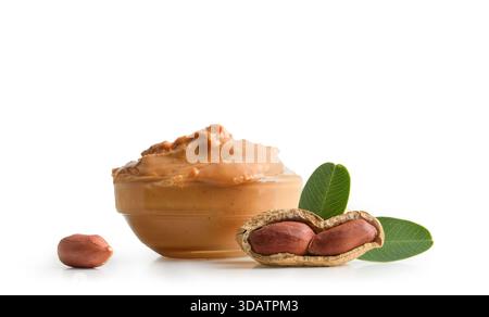 Detail der Erdnussbutter in einer Glasschale isoliert auf weißem Hintergrund mit offener Erdnuss, die Kerne und Blätter zur Dekoration zeigt. Vorderansicht. Stockfoto