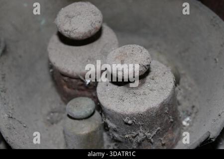 Zwei kleine, runde Gegenstände werden in einer Schüssel übereinander gelegt, die mit Staub und Schmutz bedeckt ist. Die Szene ist schwach beleuchtet, was den Eindruck von verstärkt Stockfoto