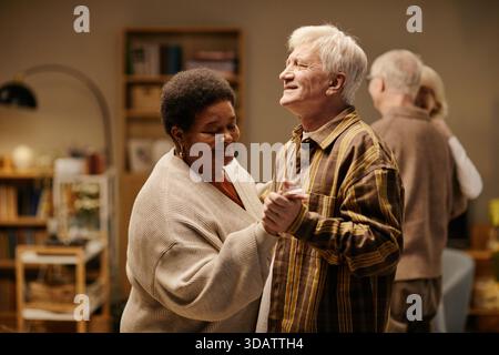 Senior kaukasischer Mann und Senior Schwarze Frau tanzen zusammen im Pflegeheim Stockfoto
