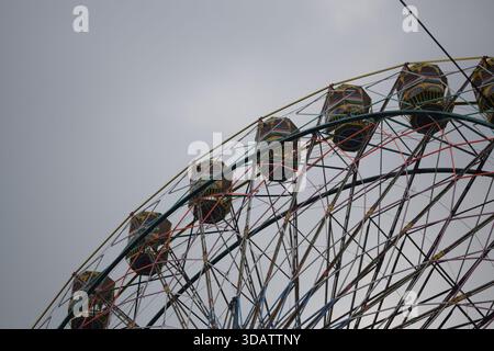 Nahaufnahme des mehrfarbigen Riesenrads während Dussehra Mela in Delhi, Indien. Unteransicht des Riesenradschwenkens. Riesenrad mit farbenfrohen Kabinen durin Stockfoto