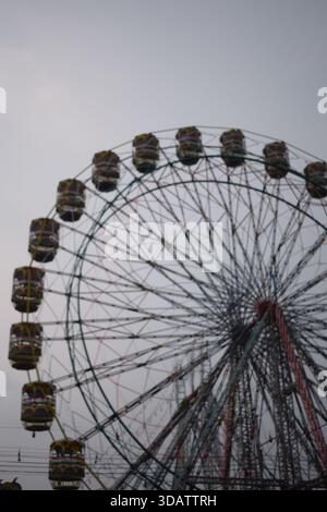 Nahaufnahme des mehrfarbigen Riesenrads während Dussehra Mela in Delhi, Indien. Unteransicht des Riesenradschwenkens. Riesenrad mit farbenfrohen Kabinen durin Stockfoto