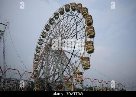 Nahaufnahme des mehrfarbigen Riesenrads während Dussehra Mela in Delhi, Indien. Unteransicht des Riesenradschwenkens. Riesenrad mit farbenfrohen Kabinen durin Stockfoto