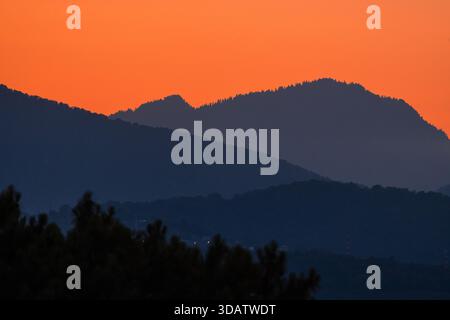 Goldener Sonnenaufgang über nebeligen Bergschichten schafft eine friedliche Landschaft im warmen Morgenlicht. Stockfoto