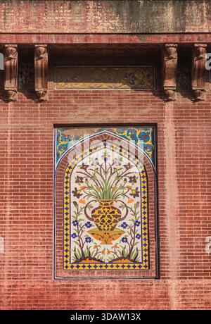 Blick auf lebendige Blumenmosaikkunst, eingerahmt in alten roten Ziegeln, kontrastierende Texturen und Farben erinnern an ein Gefühl von Geschichte und Kultur, Lahore, Punjab, Stockfoto