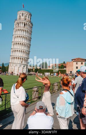 Pisa, Italien - 26. Juni 2025: Eine Gruppe von Besuchern posiert für verspielte perspektivische Fotos und hebt ihre Arme zum Schiefen Turm von Pisa als weitere Tour Stockfoto