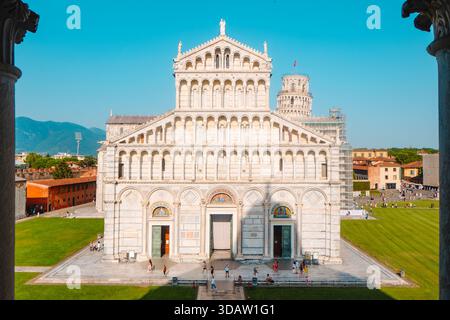 Pisa, Italien - 26. Juni 2025: Blick von einem Tauffenster, das die Kathedrale von Pisa umrahmt, wo geometrische Steinmuster, offene Türen und kleine Gruppen zu sehen sind Stockfoto