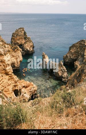 Wunderschöne Landschaften in Lagos, Algarve, Portugal. Die Farbe der Küste hebt das kristallklare Wasser hervor. Dieser Strand ist berühmt für seine felsigen Formationen. Stockfoto