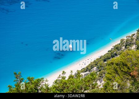 Ein Blick aus der Vogelperspektive auf einen unberührten Strand auf Lefkada, Griechenland, mit türkisfarbenem Wasser und einem kleinen Boot, das nahe der Küste ankert. Das helle mediterrane c Stockfoto