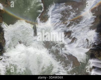 Aus der Vogelperspektive auf das kaskadierende Wasser des Quy Xuan River, ein lebhafter Regenbogen, der sich über die Wasserfälle in einem atemberaubenden Tanz aus Licht und Nebel erhebt, Cao Bang, CA Stockfoto