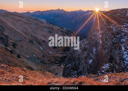 Aus der Vogelperspektive des Sonnenstrahls über dem zerklüfteten Velka Kamenista, das einen goldenen Glanz auf die Westtatra in der Region Zillina in der Slowakei ausstrahlt. Stockfoto