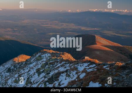 Aus der Vogelperspektive des goldenen Sonnenlichts, das die zerklüfteten Gipfel der westlichen Tatra küsst, während sich die Landschaft zum Horizont hin erstreckt, B Stockfoto