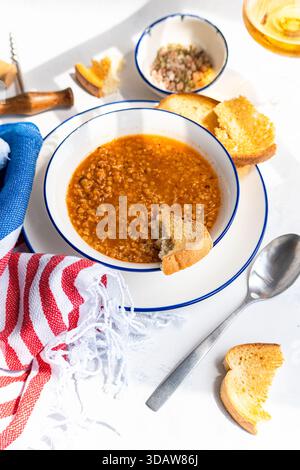 Eine köstliche Schüssel griechischer Linsensuppe, auch bekannt als Fakes, serviert mit knusprigem Brot. Dieses herzhafte und geschmackvolle Gericht ist ein Grundnahrungsmittel der griechischen Küche, per Stockfoto