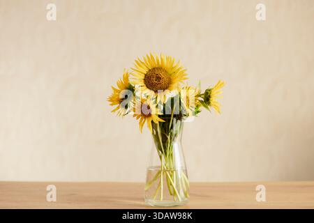 Ein lebhafter Blumenstrauß in einer klaren Glasvase, der einen Hauch von Natur in Innenräumen vermittelt. Perfekte Stillleben Komposition auf einem Holztisch A Stockfoto