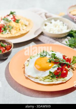 Leckere Frühstückstakos mit Spiegeleiern und Rührei, Guacamole, Salsa und Koriander bestreut. Mexikanisches Frühstück mit Huevos Rancheros Stockfoto