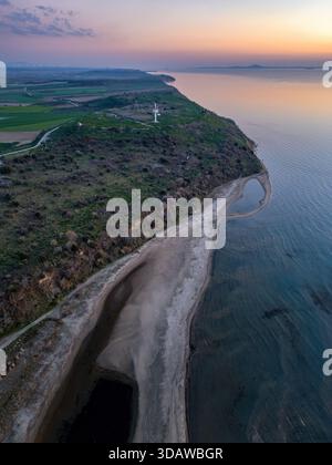Atemberaubender Blick auf das Sigeion Cape in Canakkale bei Sonnenuntergang, mit atemberaubenden Küstenklippen, ruhigem Wasser und lebendigen Farbtönen Stockfoto