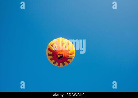 Fesselndes Bild von farbenfrohen Heißluftballons, die anmutig über die atemberaubenden weißen Terrassen von Pamukkale, Türkei, vor einem klaren blauen Himmel treiben Stockfoto