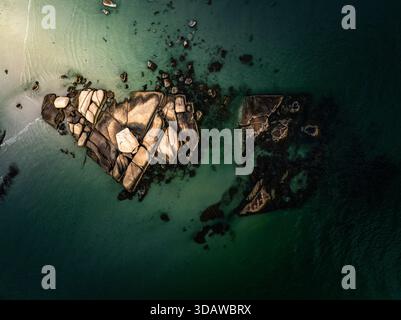 Aus der Vogelperspektive auf sonnenverwöhnte Granitblöcke, die sich aus der grünen Umarmung des Atlantiks erheben, wo Licht auf der Wasseroberfläche tanzt, Gloucester, Massac Stockfoto
