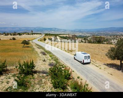 Die Drohne aus der Luft fängt einen Wohnmobil ein, der auf einer kurvenreichen Straße in der malerischen Landschaft der Türkei fährt. Die Szene zeigt das riesige und robuste Stockfoto
