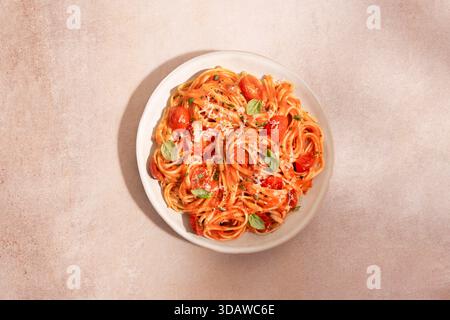 Blick von oben auf einen Teller Spaghetti-Pasta, bedeckt mit reichhaltiger Tomatensauce, garniert mit Kirschtomaten, frischem Basilikum und geriebenem Parmesankäse auf einem Text Stockfoto