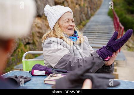Ein älteres Ehepaar genießt einen Wintertag im Freien, warm gekleidet mit Hüten und Handschuhen. Sie lächeln und nehmen an Aktivitäten teil, zeigen Freude und Stockfoto