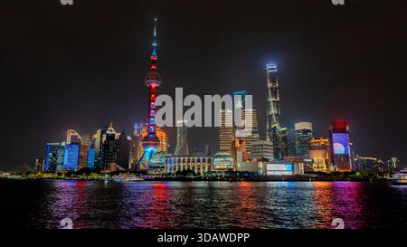Die pulsierende Skyline von Shanghai wird von bunten Lichtern beleuchtet, die sich vom Wasser reflektieren. Legendäre Wolkenkratzer schaffen eine atemberaubende Stadtlandschaft gegen die Stockfoto