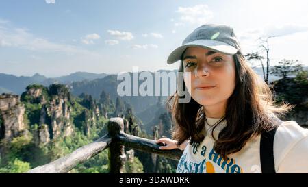 Eine Frau steht an einem Aussichtspunkt in Yuanjiajie, Teil von Zhangjiajies Wulingyuan Scenic Area in China, und genießt die spektakulären Karstsäulenformationen u Stockfoto