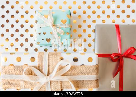 Wunderschön gewickelte Geschenkboxen mit Bändern auf festlichem goldenen Polka Dot Hintergrund. Helle und fröhliche Ferienwohnung. Perfekt für Feiern, Geschenke Stockfoto