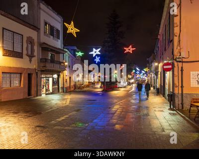 San Cristobal de La Laguna, Spanien - 17. Dezember 2016: Blick auf eine ruhige Straße mit funkelnden Weihnachtssternen, während zwei Figuren unter dem W spazieren Stockfoto