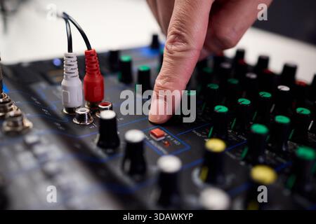 Tastfinger bedienen die beleuchteten Drehregler während der Soundcheck-Einrichtung, professionelle Techniker stellen die Soundausrüstung mit mehreren angeschlossenen Kabeln fertig Stockfoto