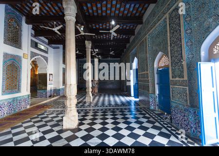 Bhit Shah, Pakistan - 05. Dezember 2025: Blick auf die Innenhalle mit karierten Böden, verzierten blau-weiß gefliesten Wänden und hohen weißen Säulen Stockfoto