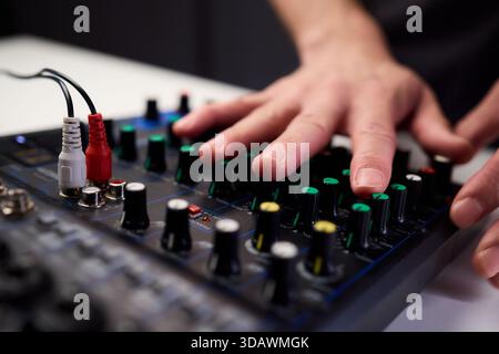 Tastfinger bedienen die beleuchteten Drehregler während der Soundcheck-Einrichtung, professionelle Techniker stellen die Soundausrüstung mit mehreren angeschlossenen Kabeln fertig Stockfoto