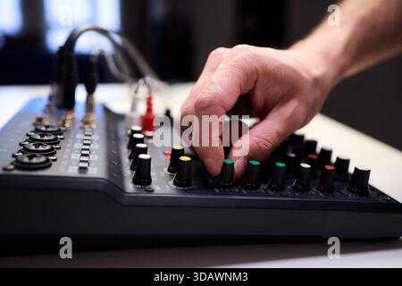 Tastfinger bedienen die beleuchteten Drehregler während der Soundcheck-Einrichtung, professionelle Techniker stellen die Soundausrüstung mit mehreren angeschlossenen Kabeln fertig Stockfoto